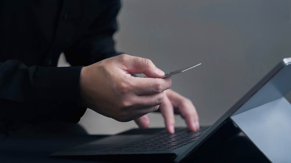 Hands holding credit card at a laptop