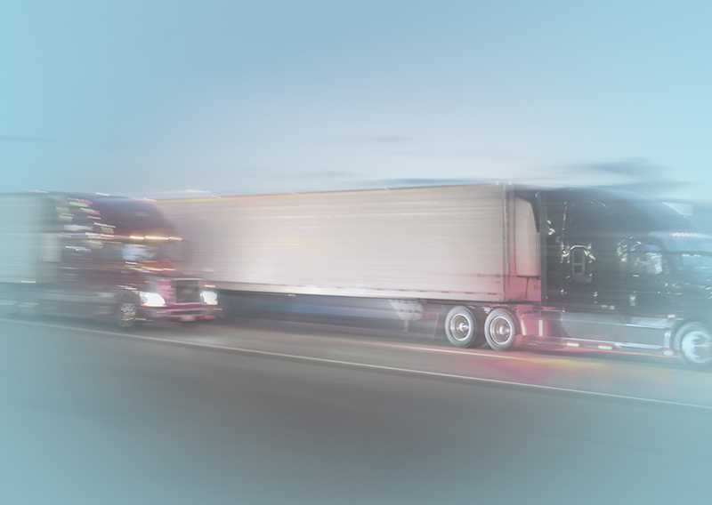 Trucks driving down a highway side by side.