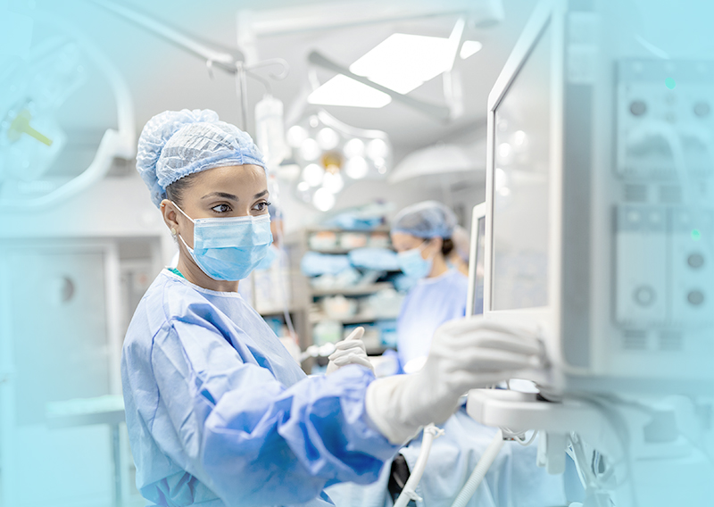 Nurse in scrubs working and using a medical device.